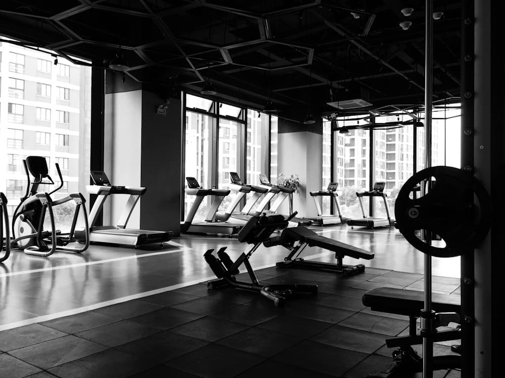 Weight training area with benches and plates beside floor-to-ceiling windows