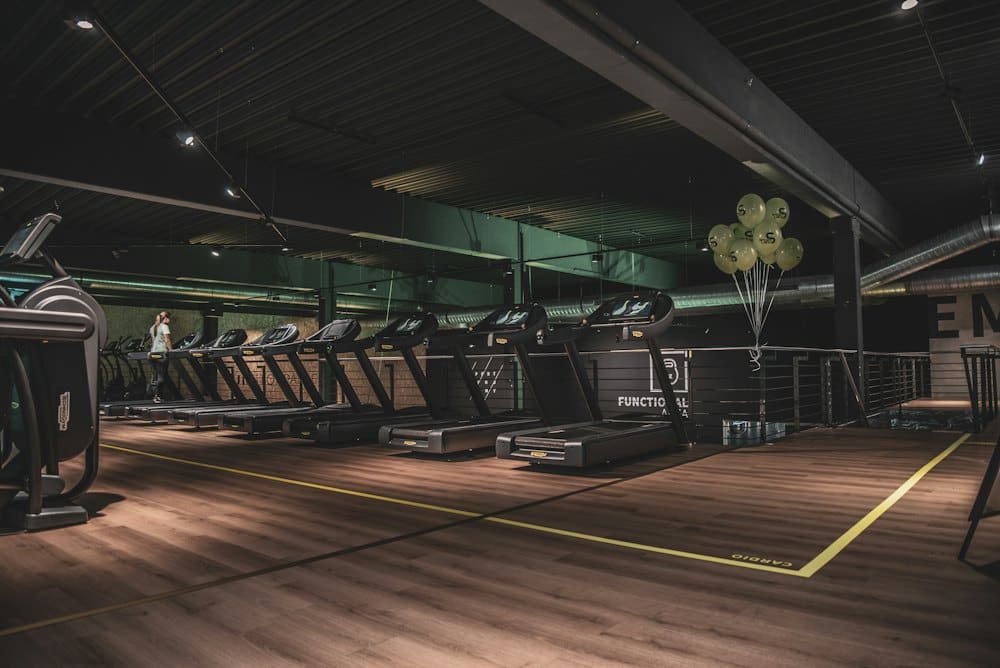 Row of treadmills and cardio machines with yellow floor markings