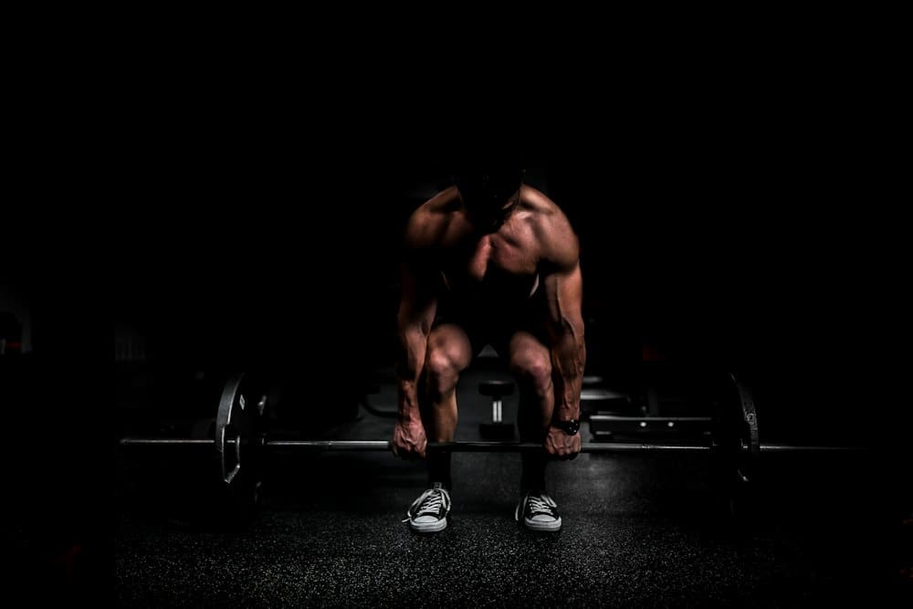 Athlete mid-rep with a barbell under dramatic dark lighting