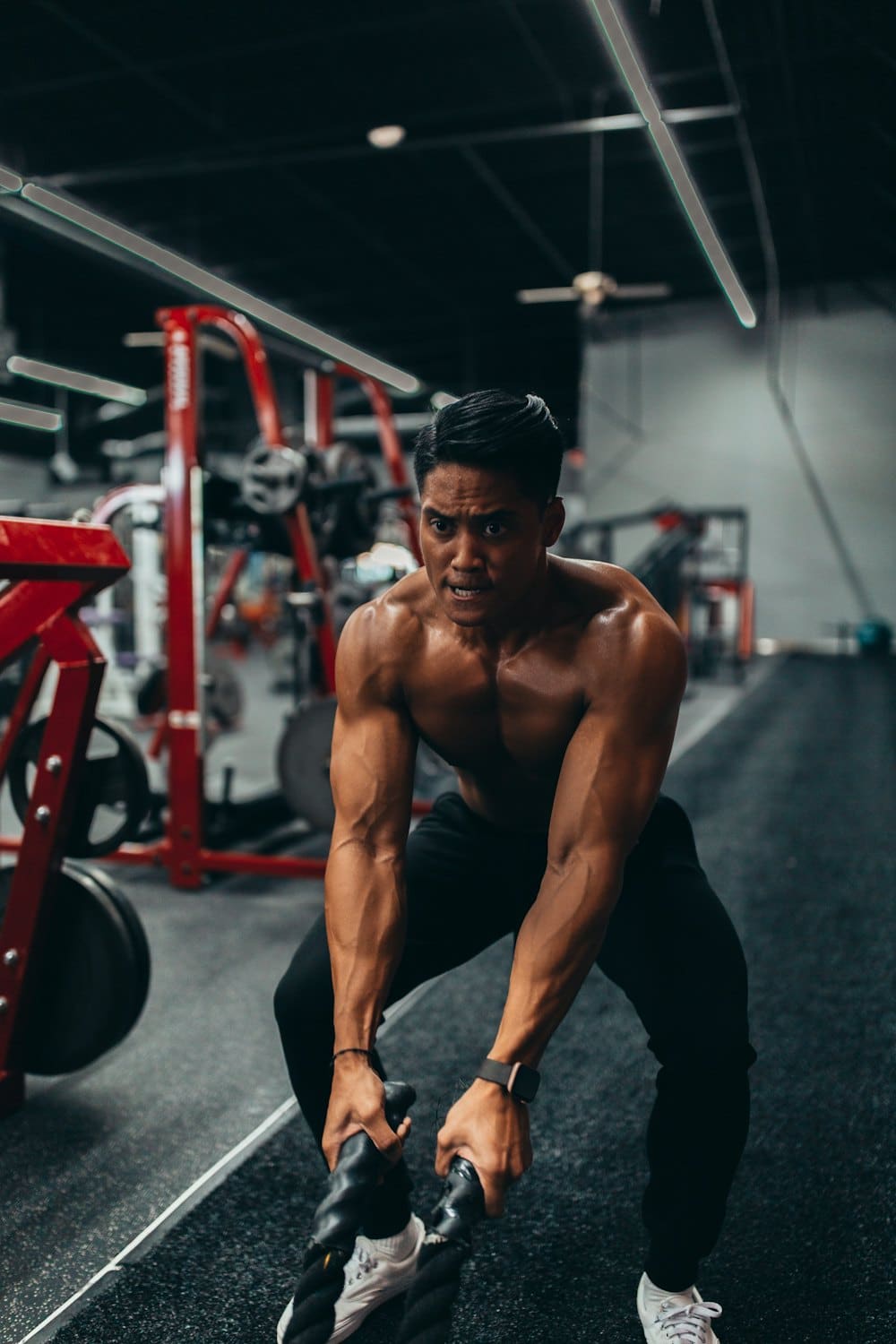 Coach Leo training with battle ropes in a dark gym