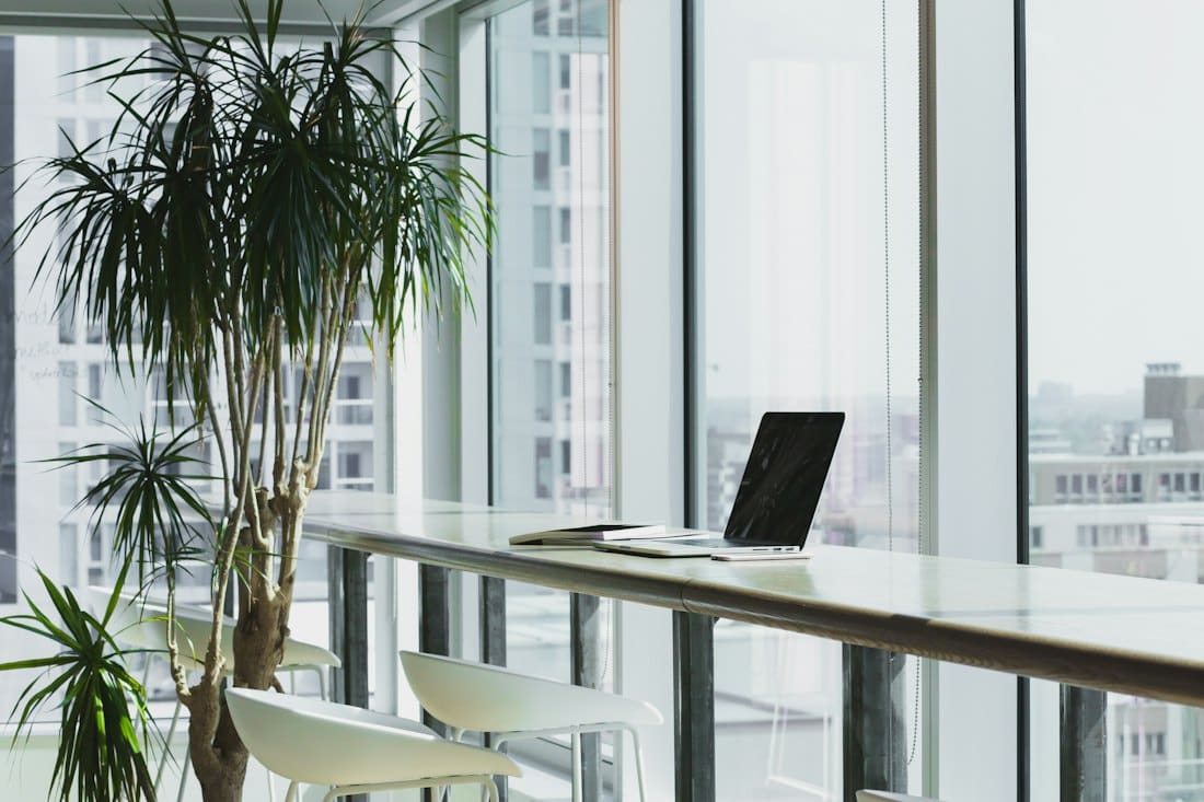 Bright open-plan office with desks beside floor-to-ceiling windows