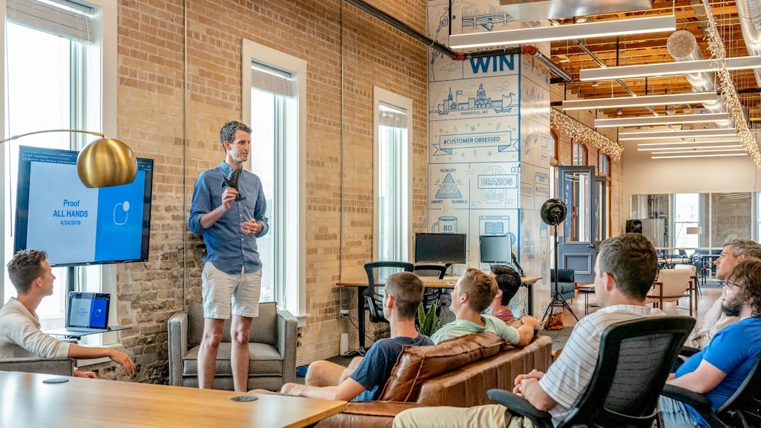 Presenter speaking to colleagues in a brick-walled loft office