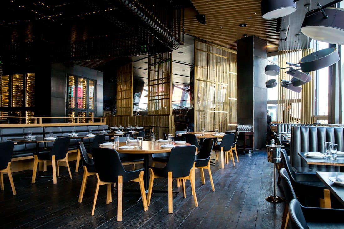 Contemporary restaurant dining room with dark chairs and warm lighting