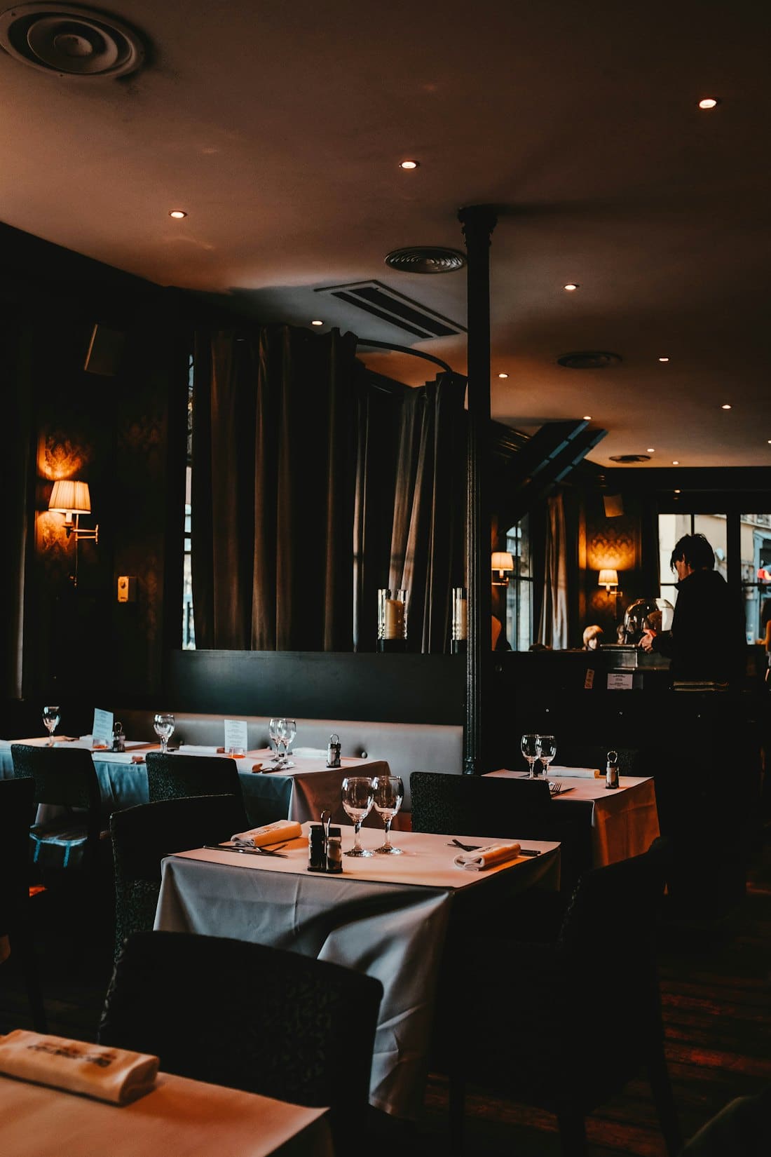 Dimly lit dining room with white tablecloths and wine glasses