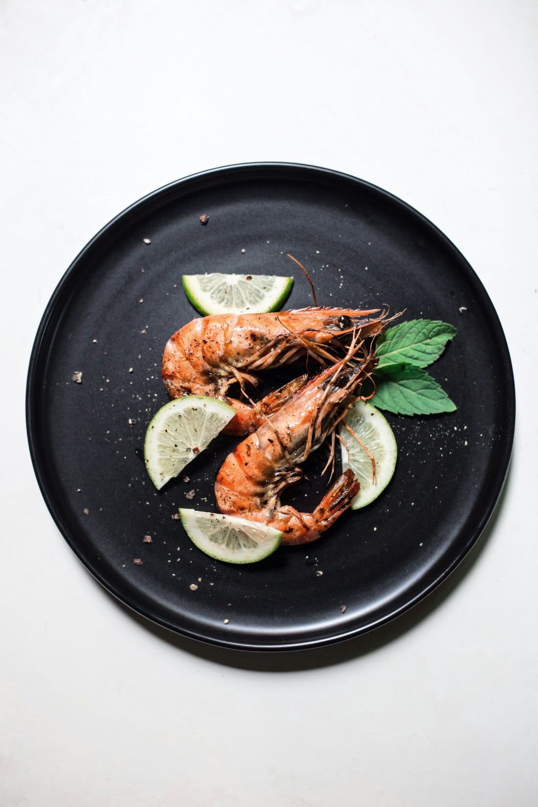 Grilled prawns with lemon on a black plate