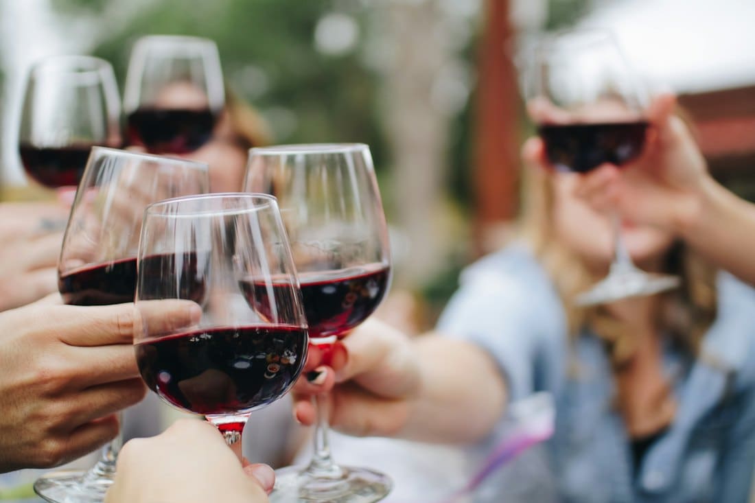 Guests raising glasses of red wine in a toast