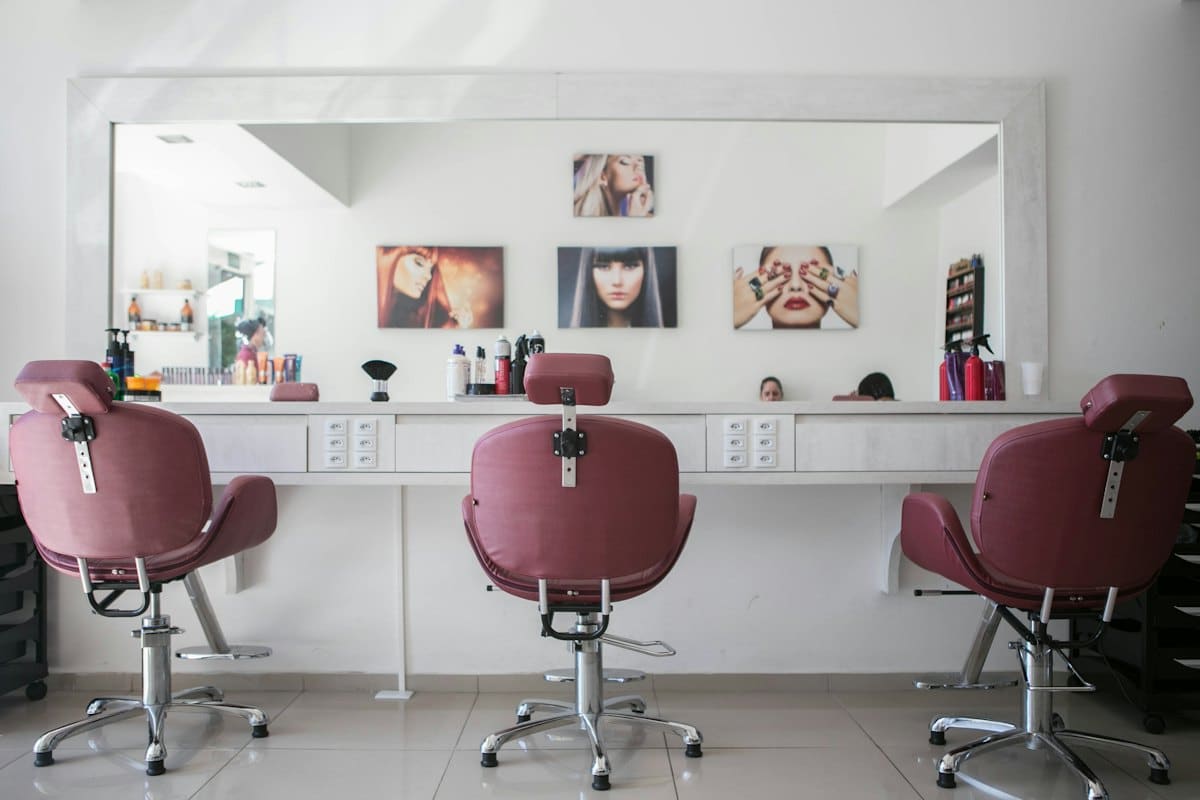 Row of blush velvet styling chairs facing a long salon mirror