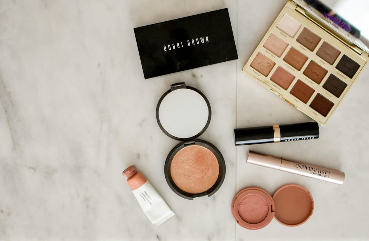 Neutral makeup palette, blush and lipstick arranged on marble